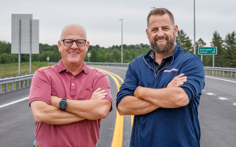 Two pose outside on a road.
