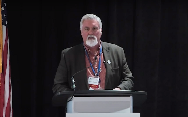 Mark Swann speaks at a podium.