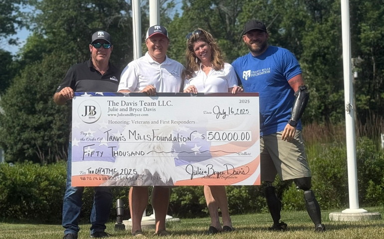Four people pose wtih an oversize check.