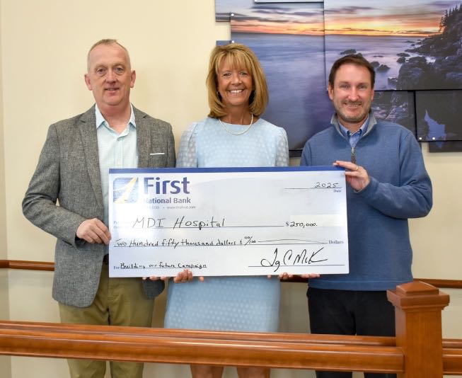 Three people pose in a line with an oversize check.