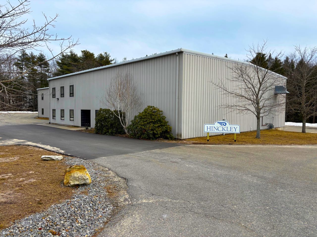 A tan building has a sign and driveway out front.