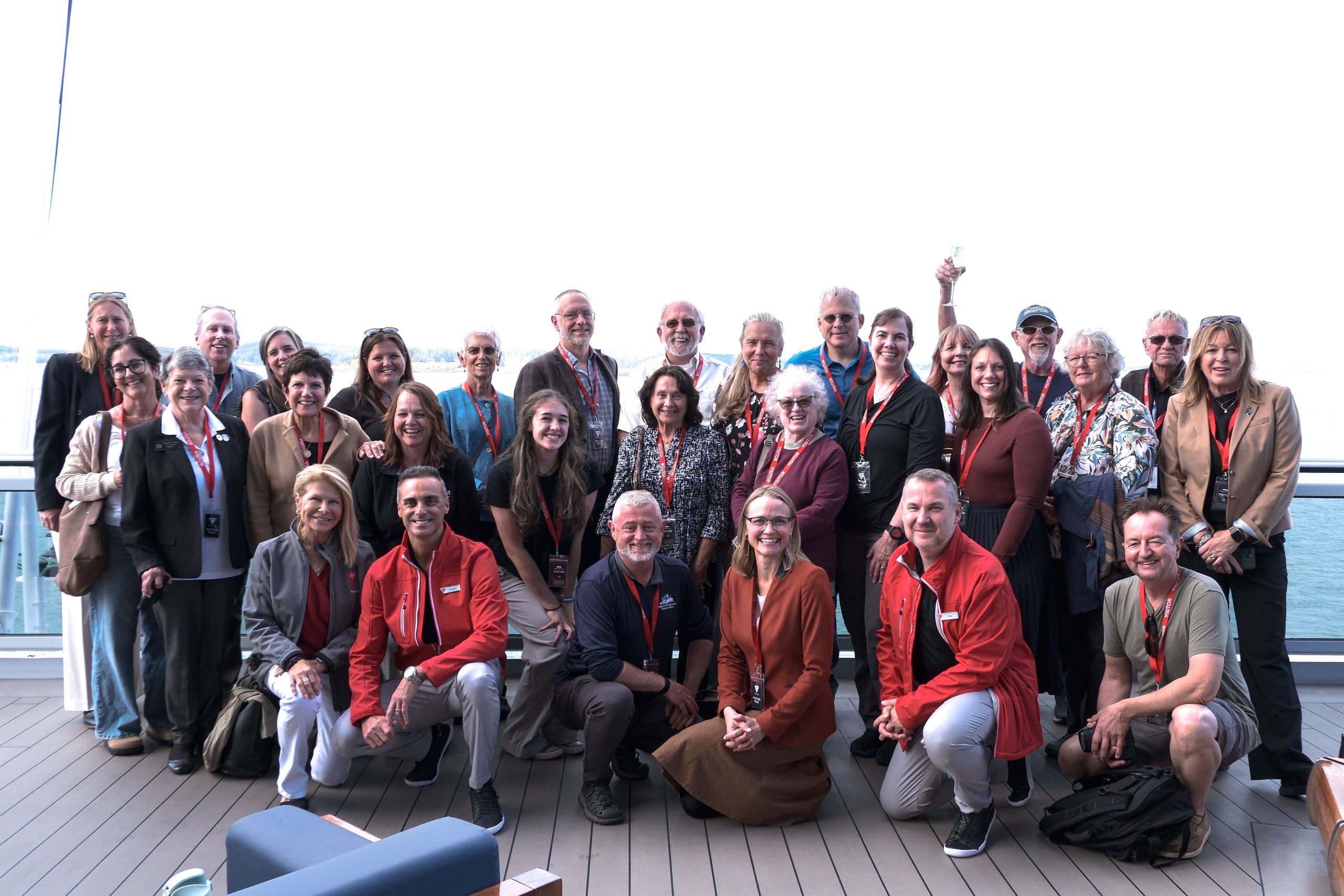 A group of people pose in lines on a deck.