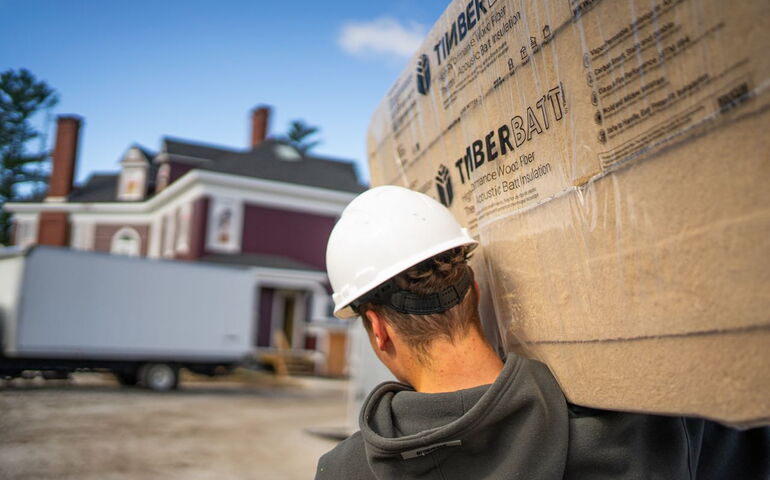 A person carries plastic-wrapped wood.