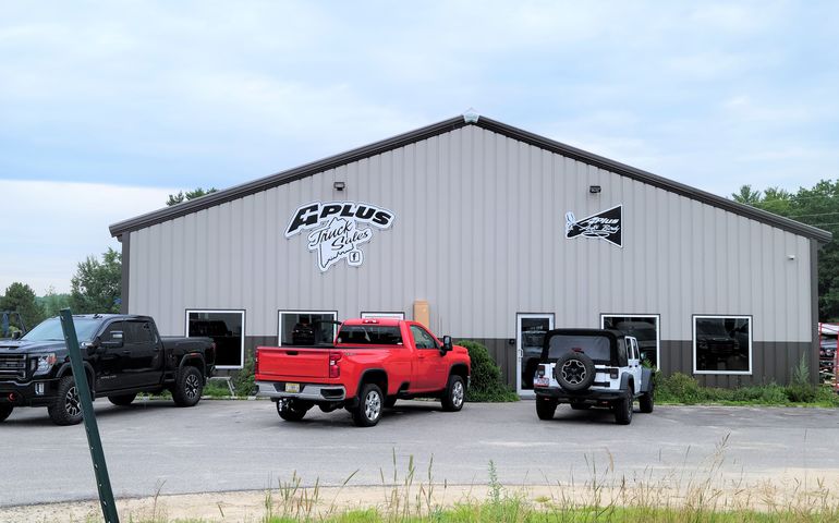 Front of A Plus Truck Sales dealership - warehouse like building with trucks parked in front