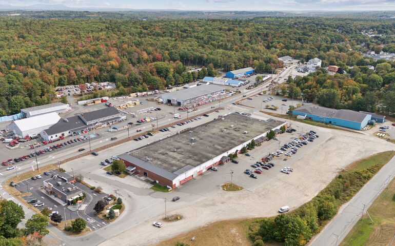 An aerial view shows a shopping center and road.