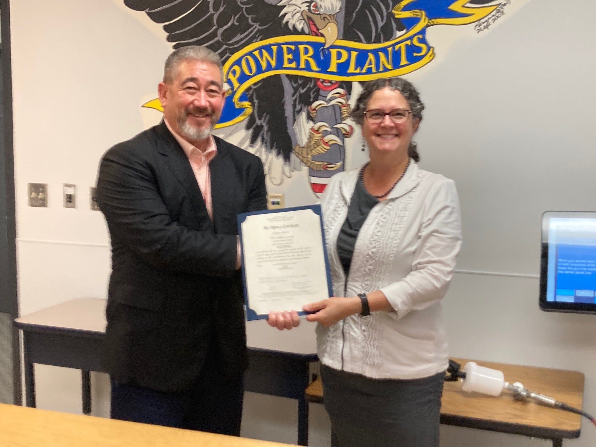 Two people hold a certificate for UMA's aviation school.