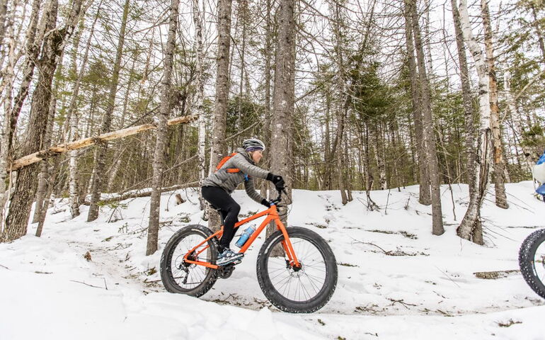 A person on a bike cycles through the snow.