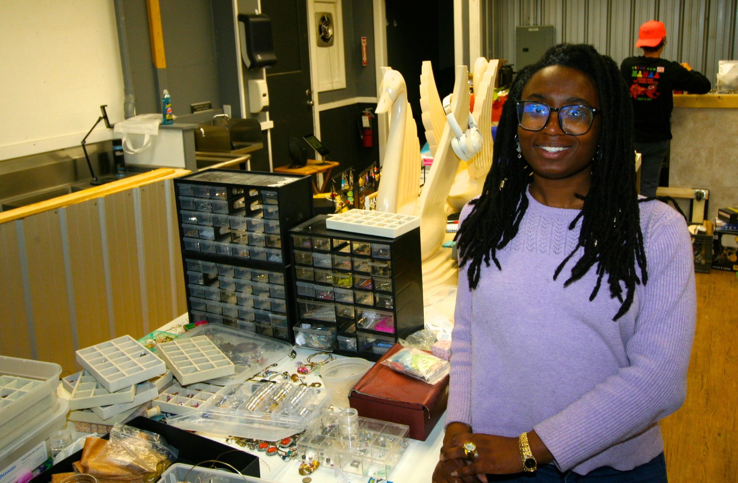 A person stands near a table with jewelry.