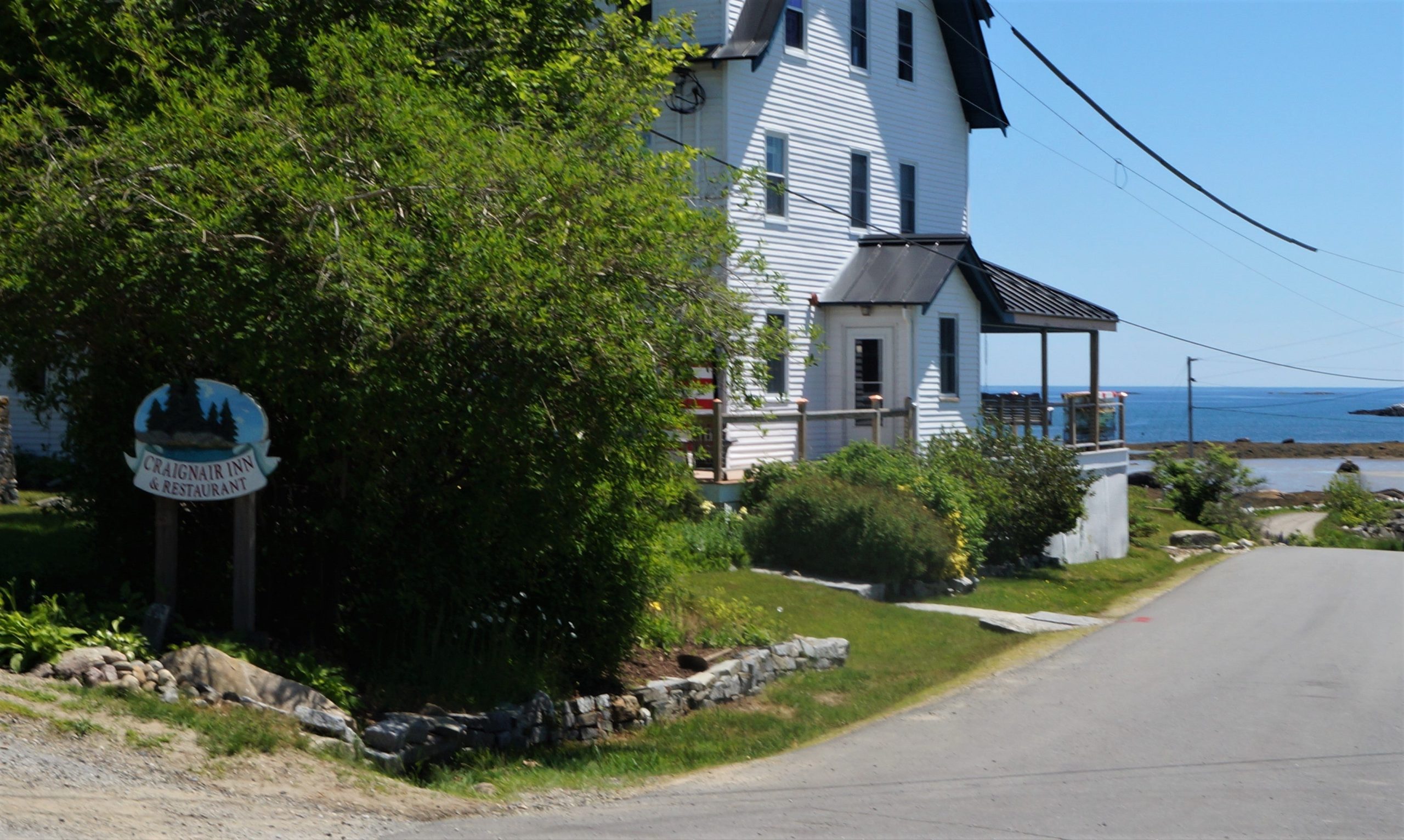 an inn with the ocean in the background an sign that sais Craignair Inn and Restaurant
