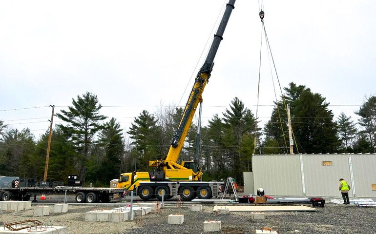 A crane is at a construction site with a person standing by.
