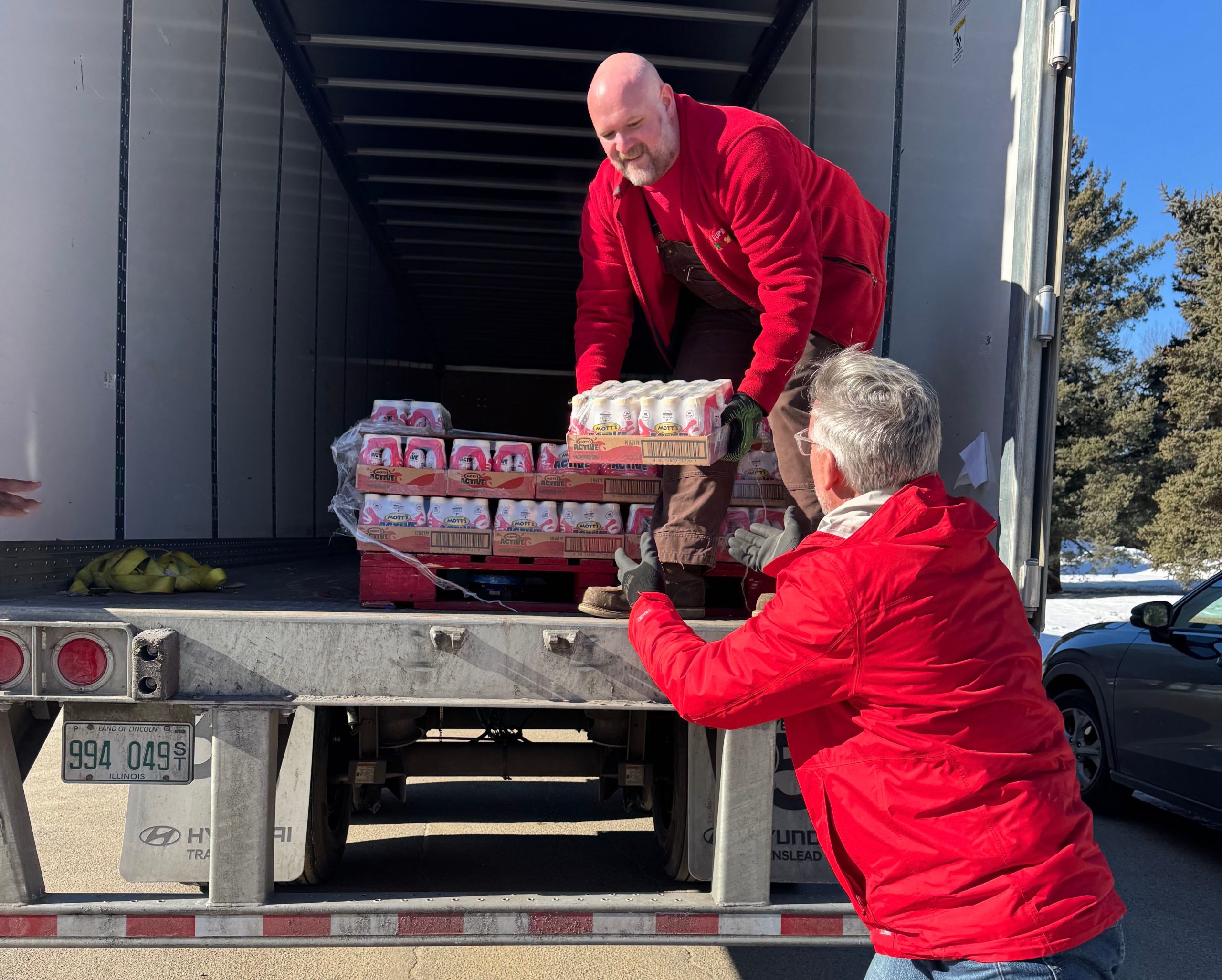 Two people unload goods from a truck.