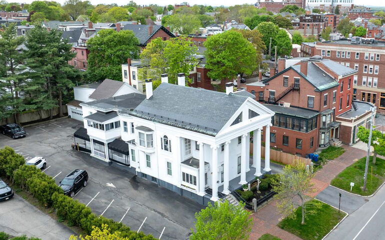 An aerial view shows a white building with pillars.
