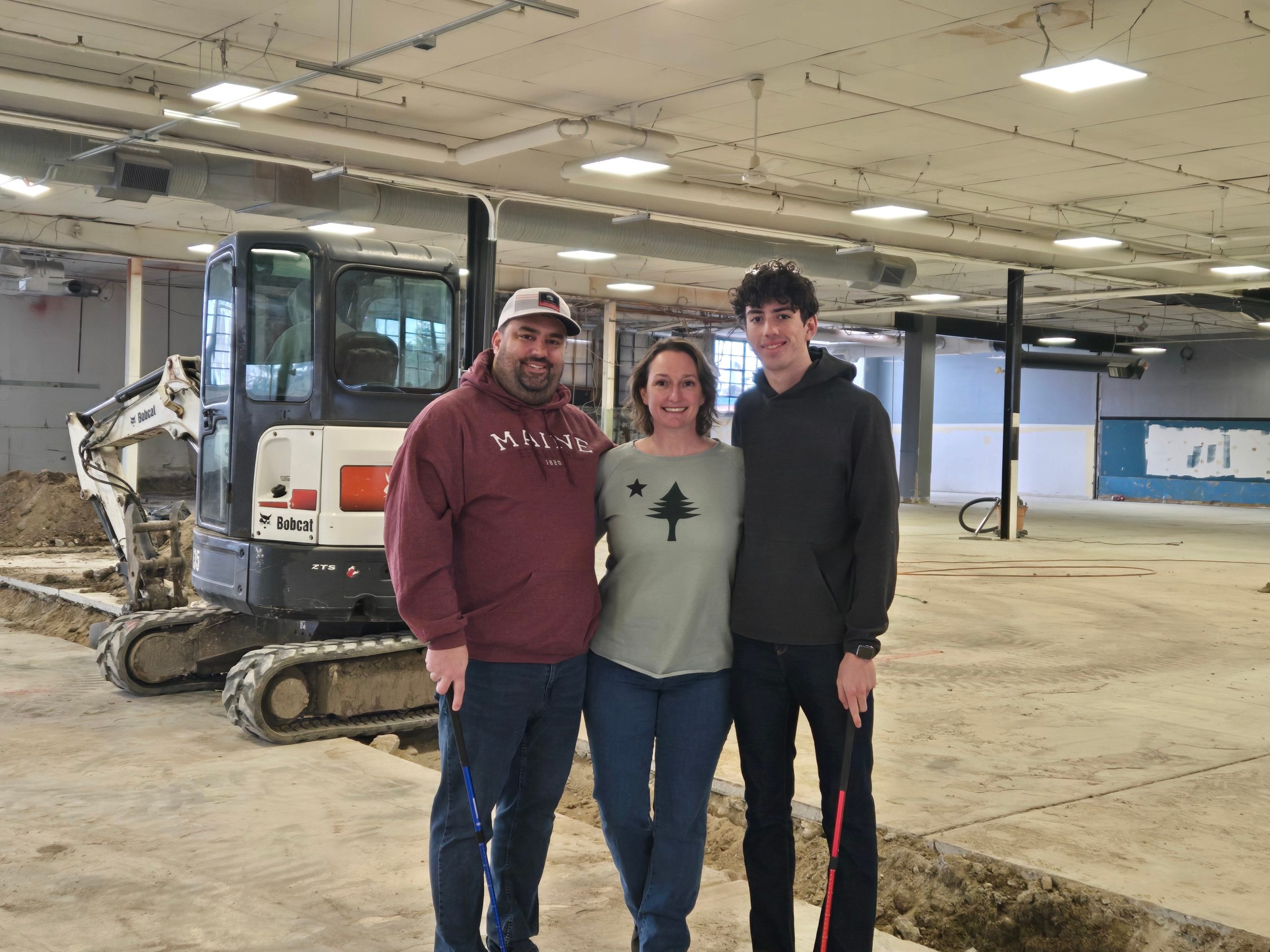 Three people standing inside a building where construction is underway.