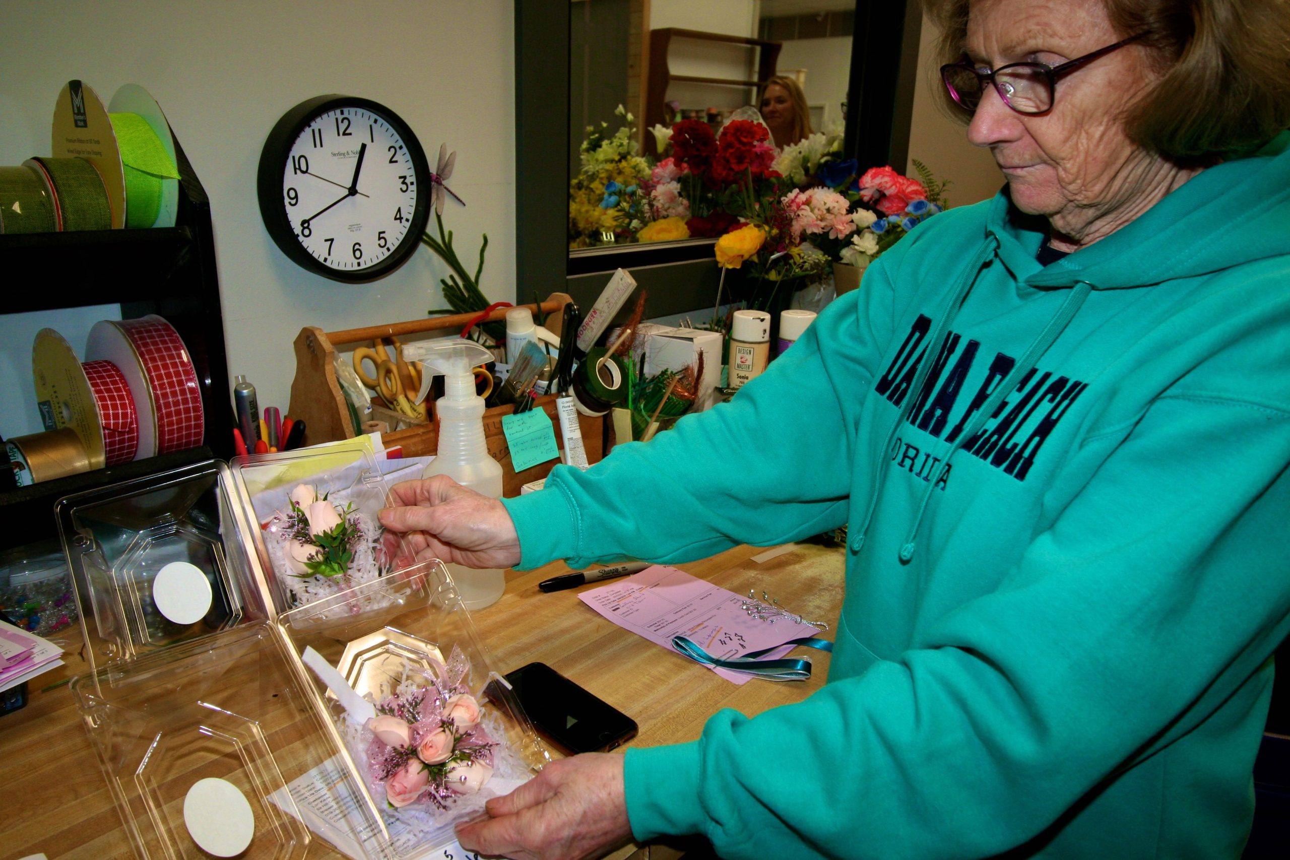 A persn holds a plastic box with flowers.
