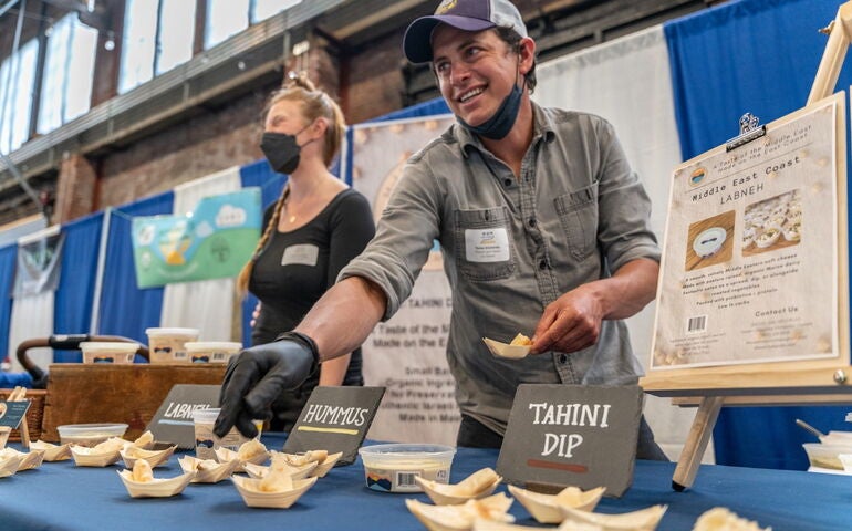 Two people work at a food table.