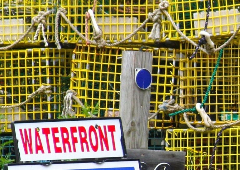 A sign is in front of stacks of lobster traps.