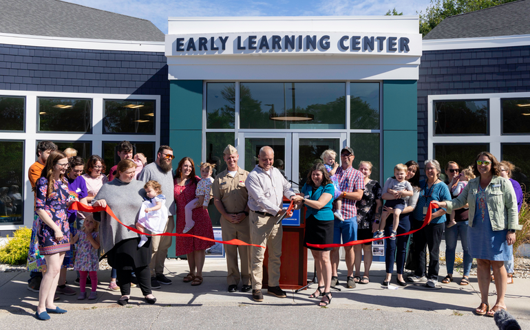 People pose in a grouping and cut a red ribbon.