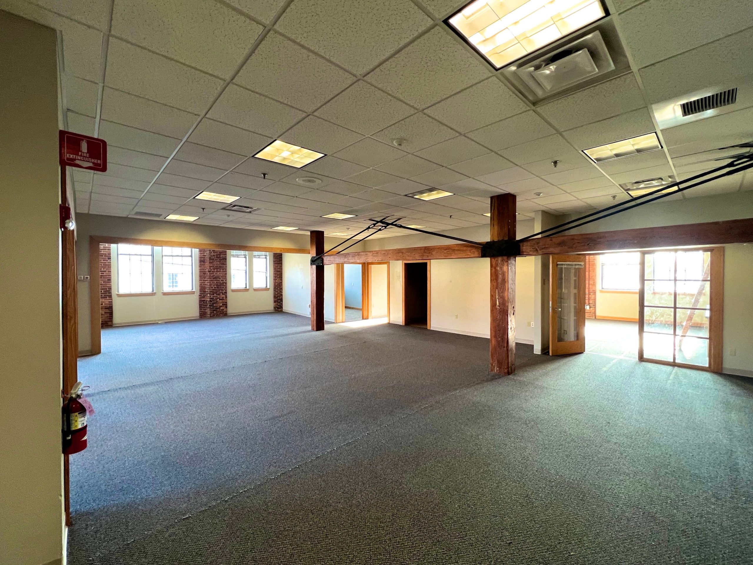 An interior view shows an empty room with wood posts and beams.