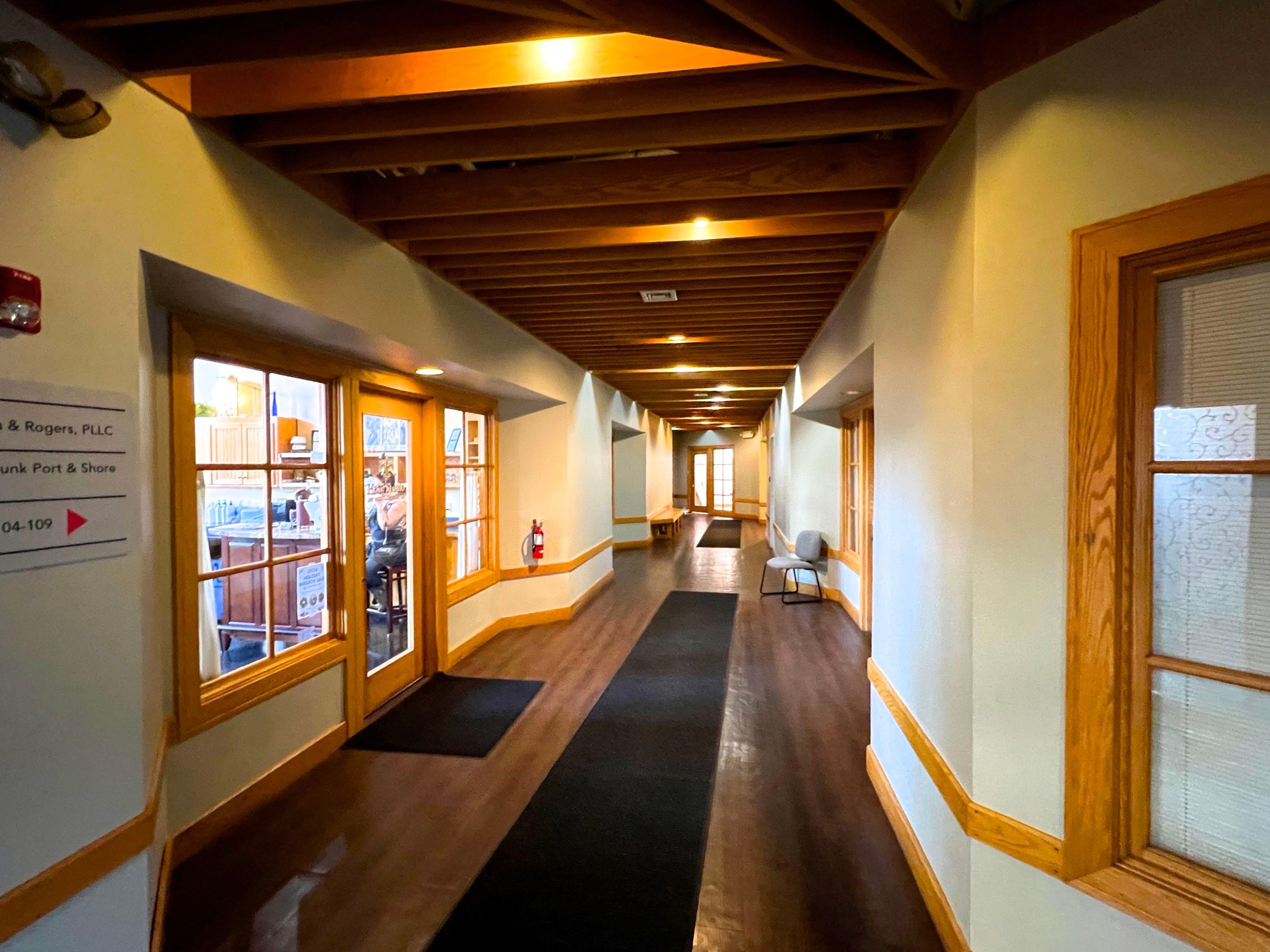 A hallway has white walls with wood trim and a wood floor.