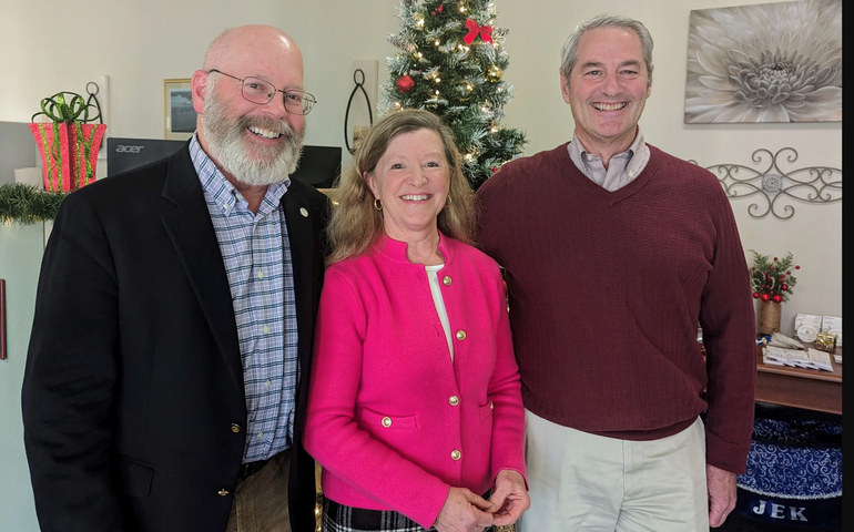 Three people pose in an office.