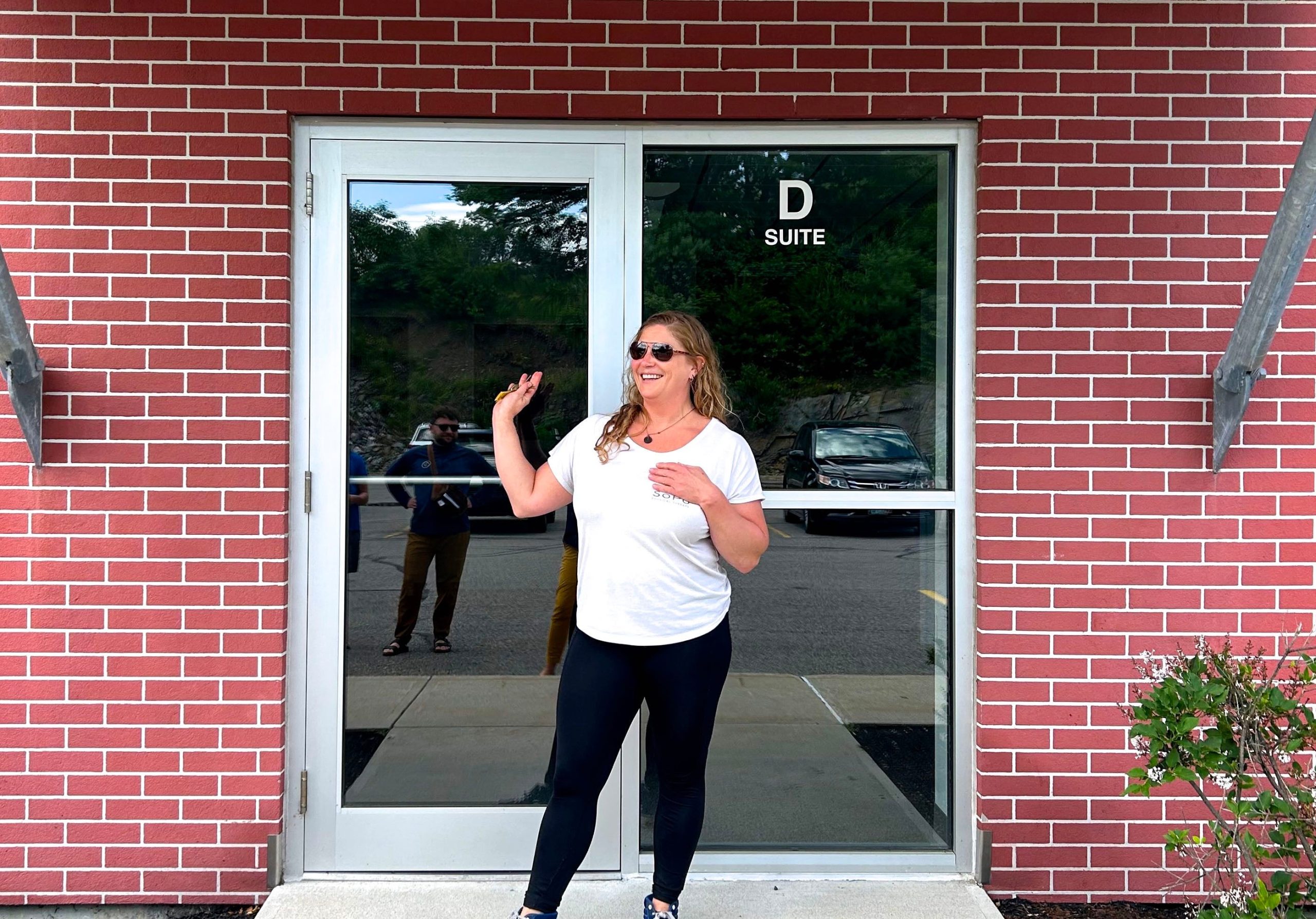 person in white T-shirt smiling and posing in front of doorway