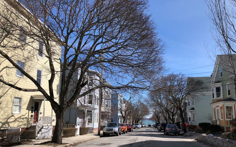 A row of triple-decker type apartment buildings on a city street
