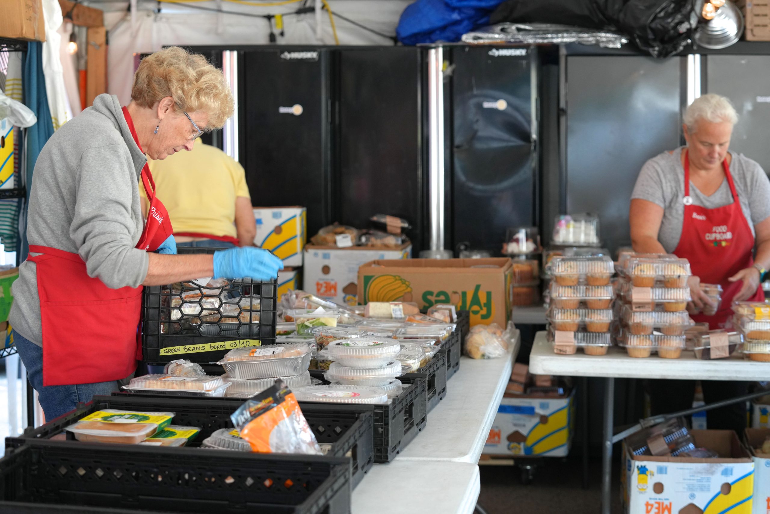 Two people unpack food at tables.
