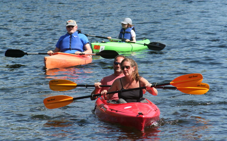 People are in kayaks paddling on the water.
