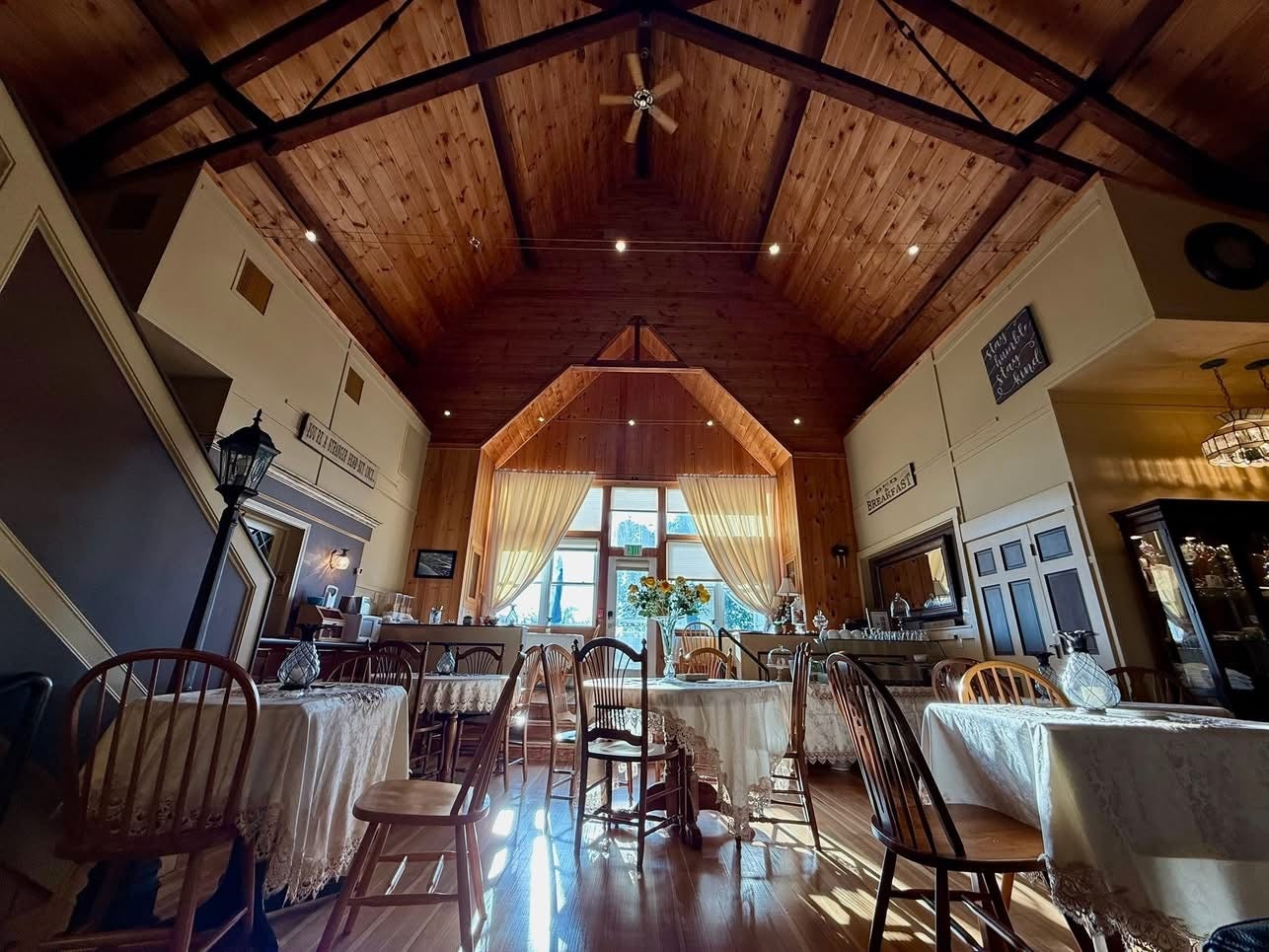 A room has a high ceiling and tables and chairs.