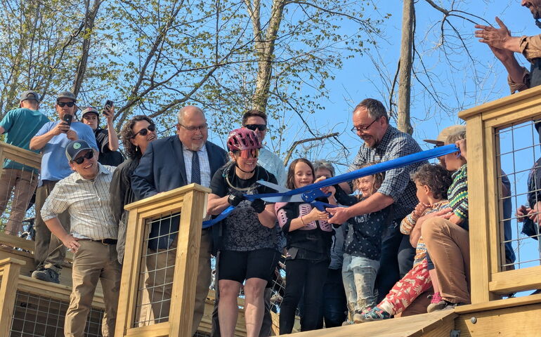People stand on a structure and cut a ribbon.