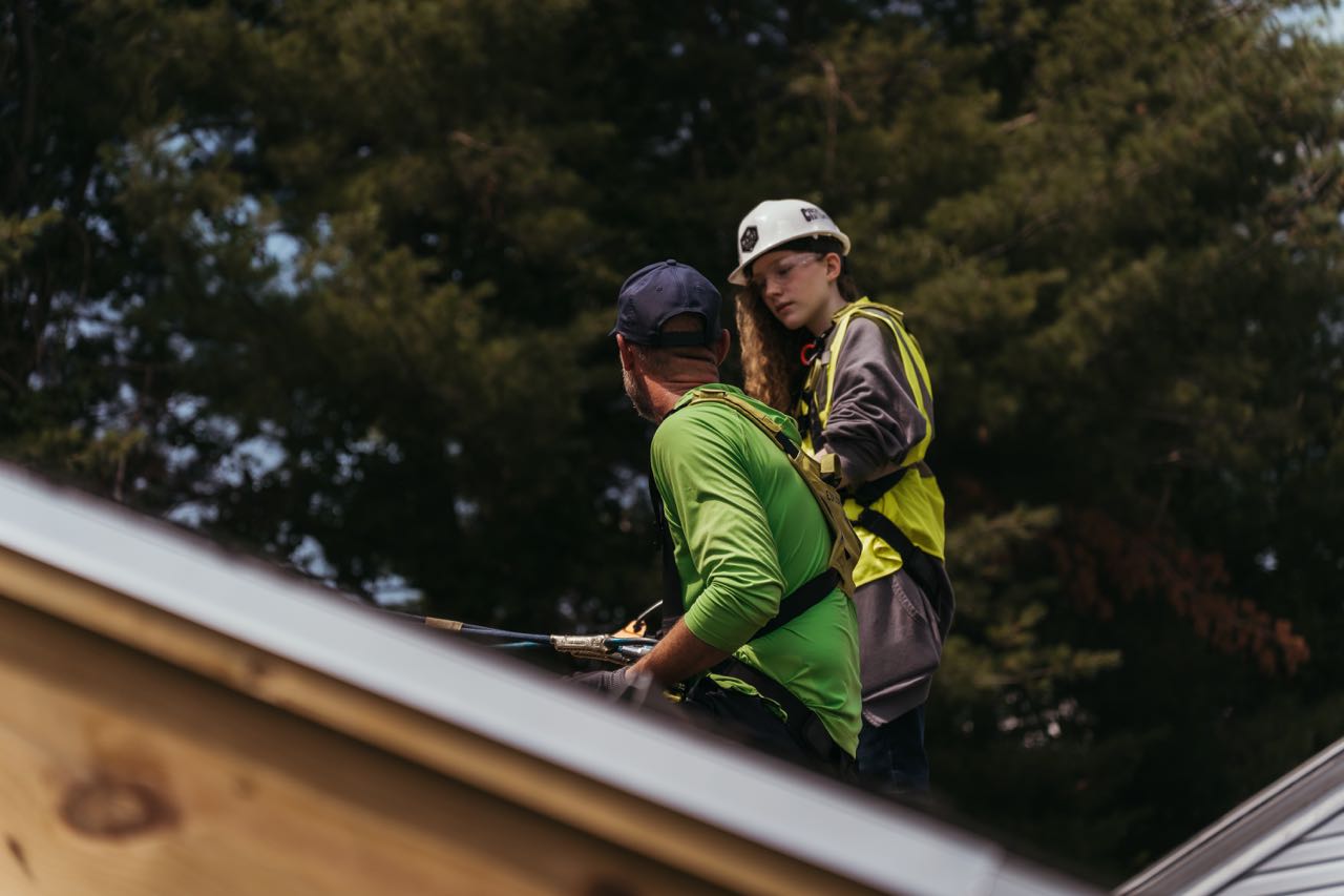 Two people on the roof are part of a training session.