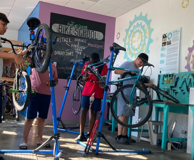 People work on bikes that are on stands.