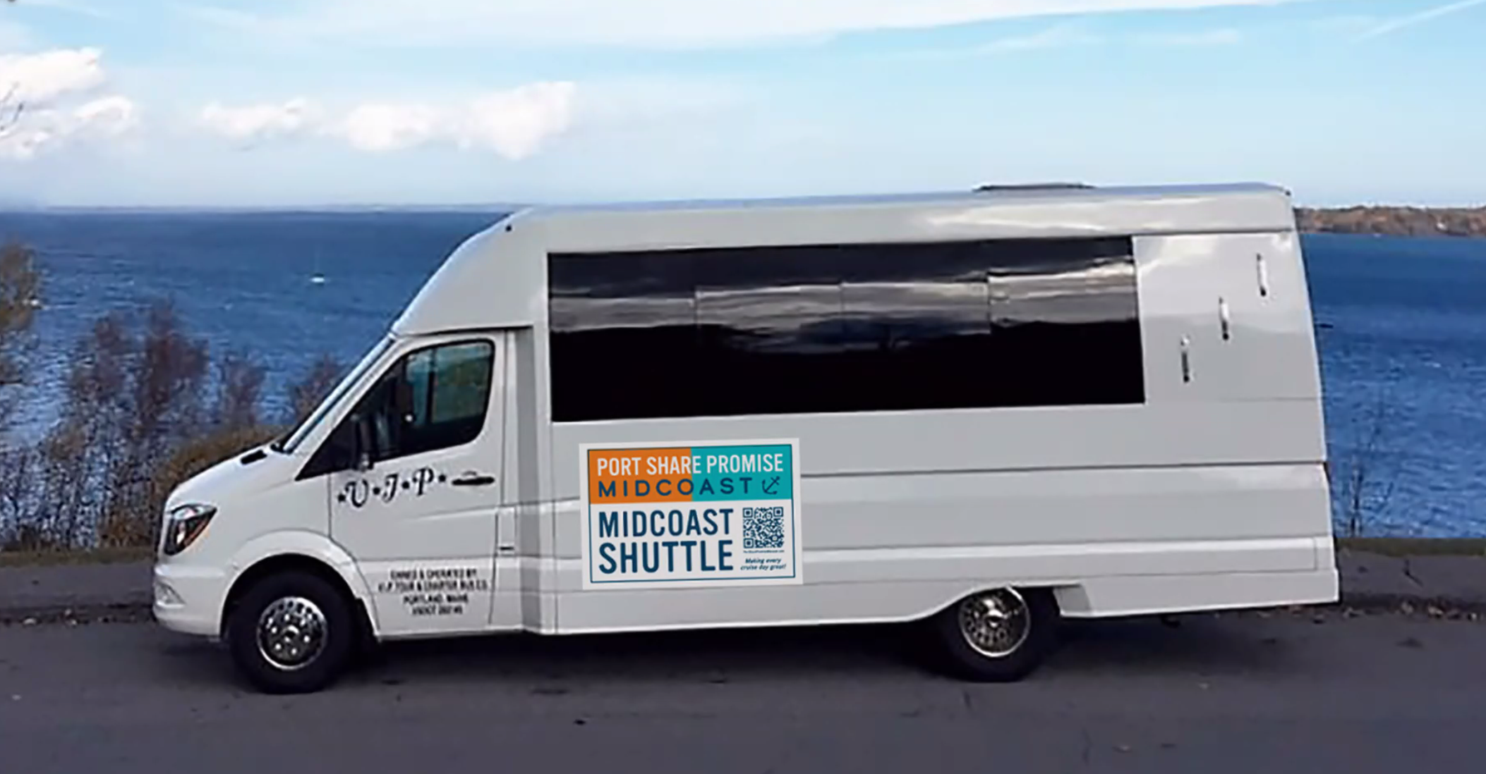 A van sits on a road by the sea.