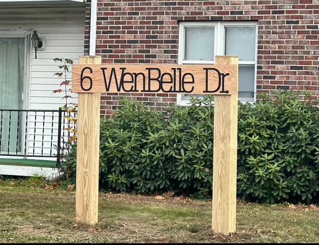 A wood sign stands outside of a building.