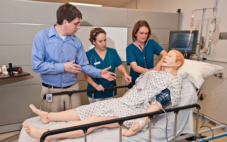3 people with dummy in bed