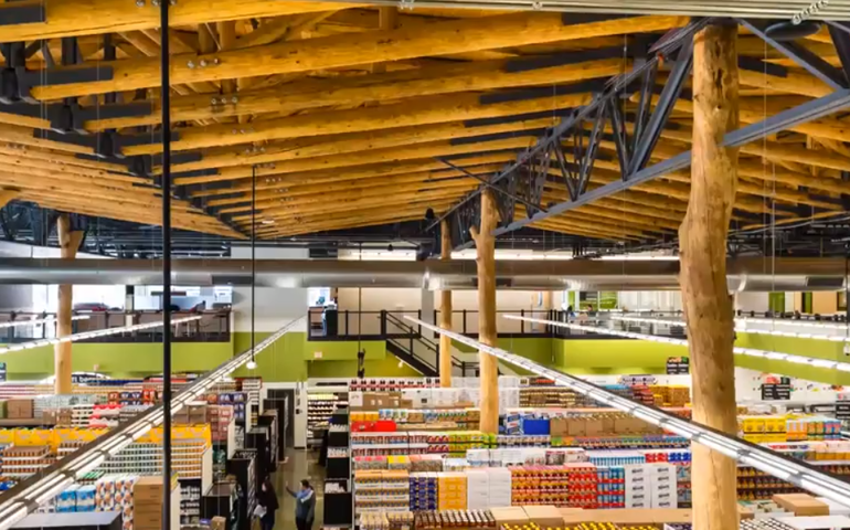 a large warehouse with a ceiling made of stripped logs, as well as posts that look like trees with no bark