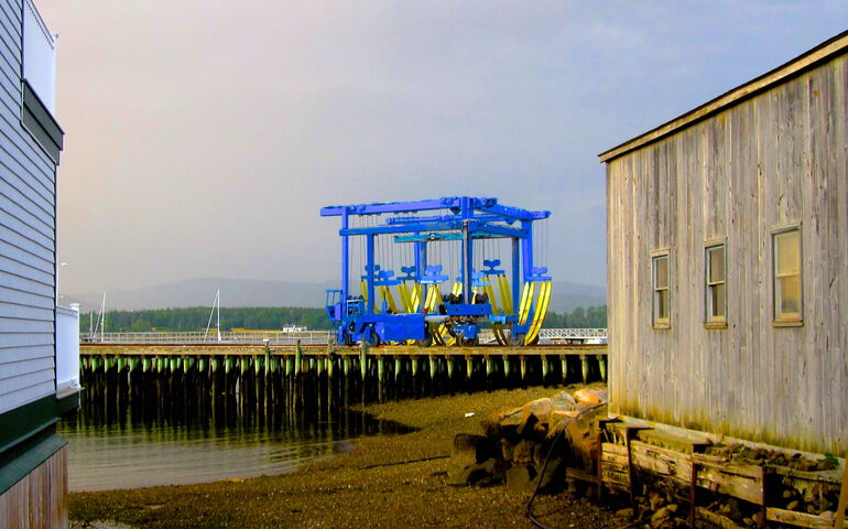 A large vehicle with straps is seen on a wharf.