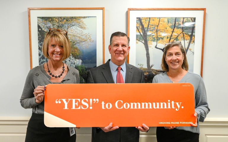 three people holding orange sign 