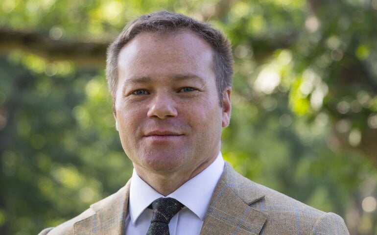 person in tan sportscoat smiling