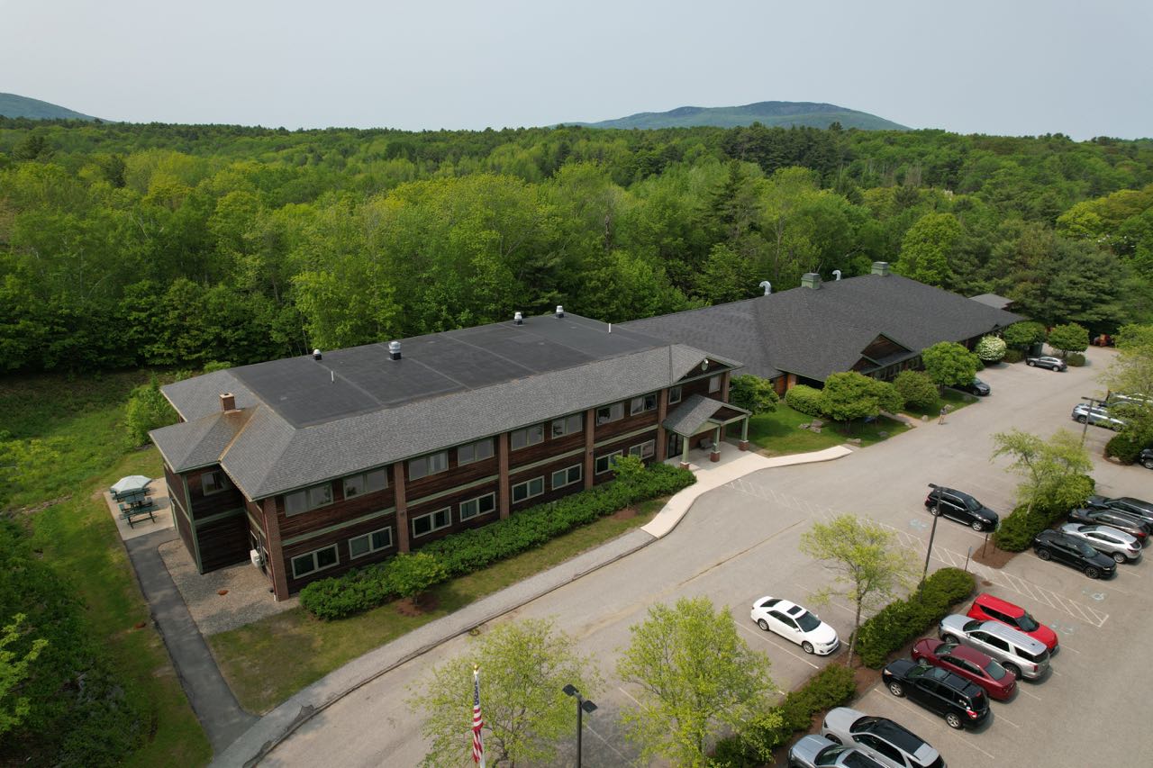 An aerial view of a long building and parking lot.