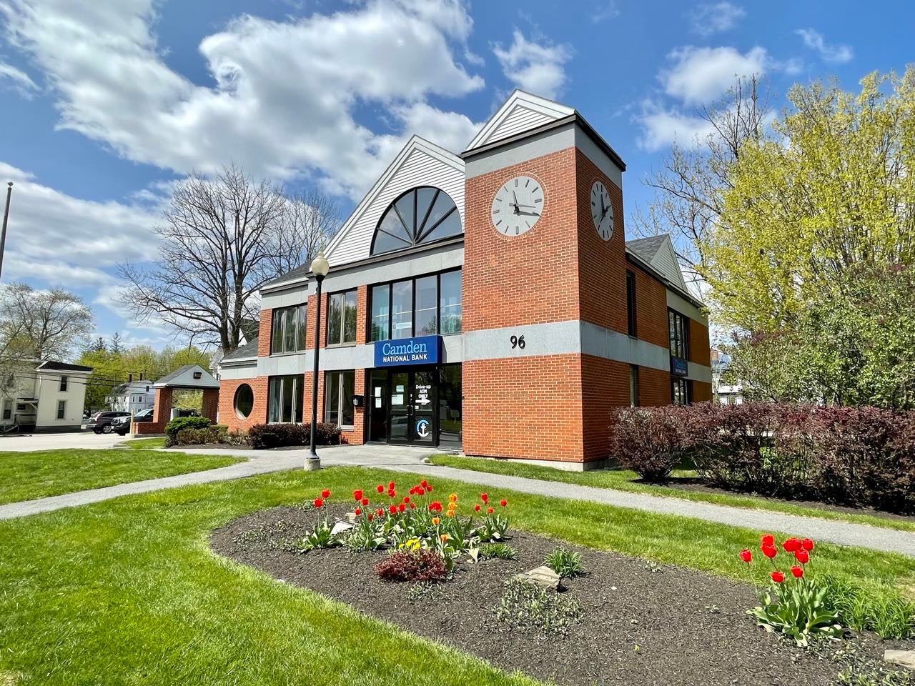 An exterior view of a brick building with tower and lawn.