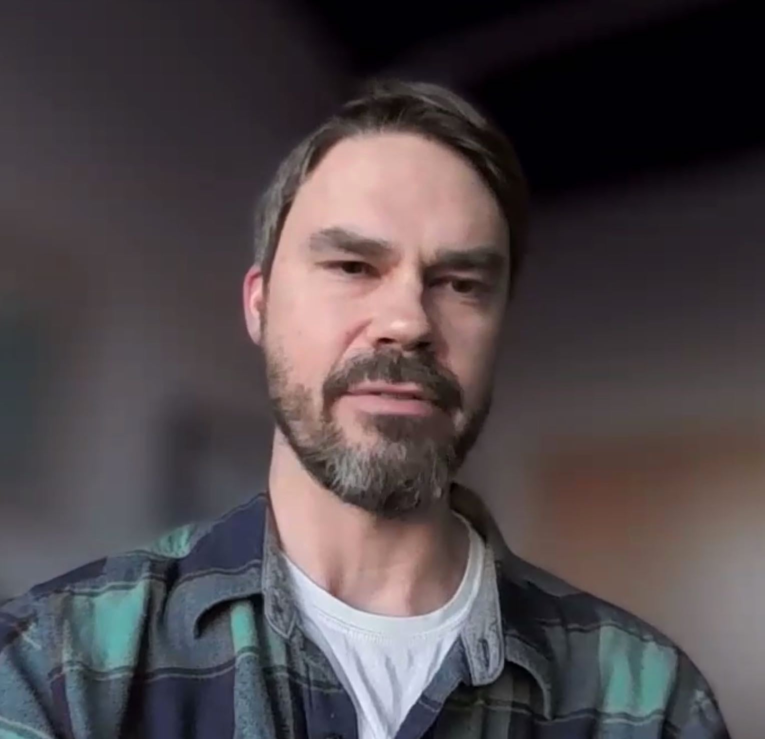 A person wearing a plaid shirt is talking.