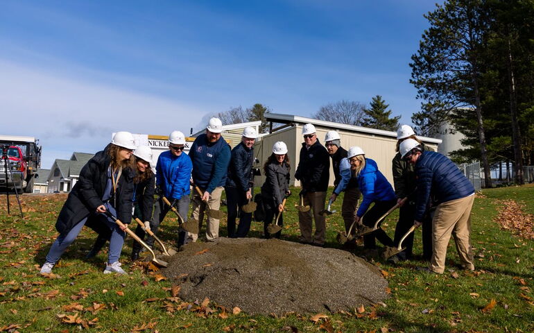 People pose in a line with shovels.