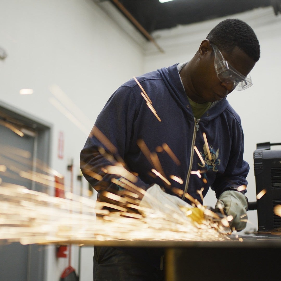 A person works with a tool that causes sparks.