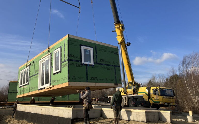 People pull a wooden box onto a foundation.