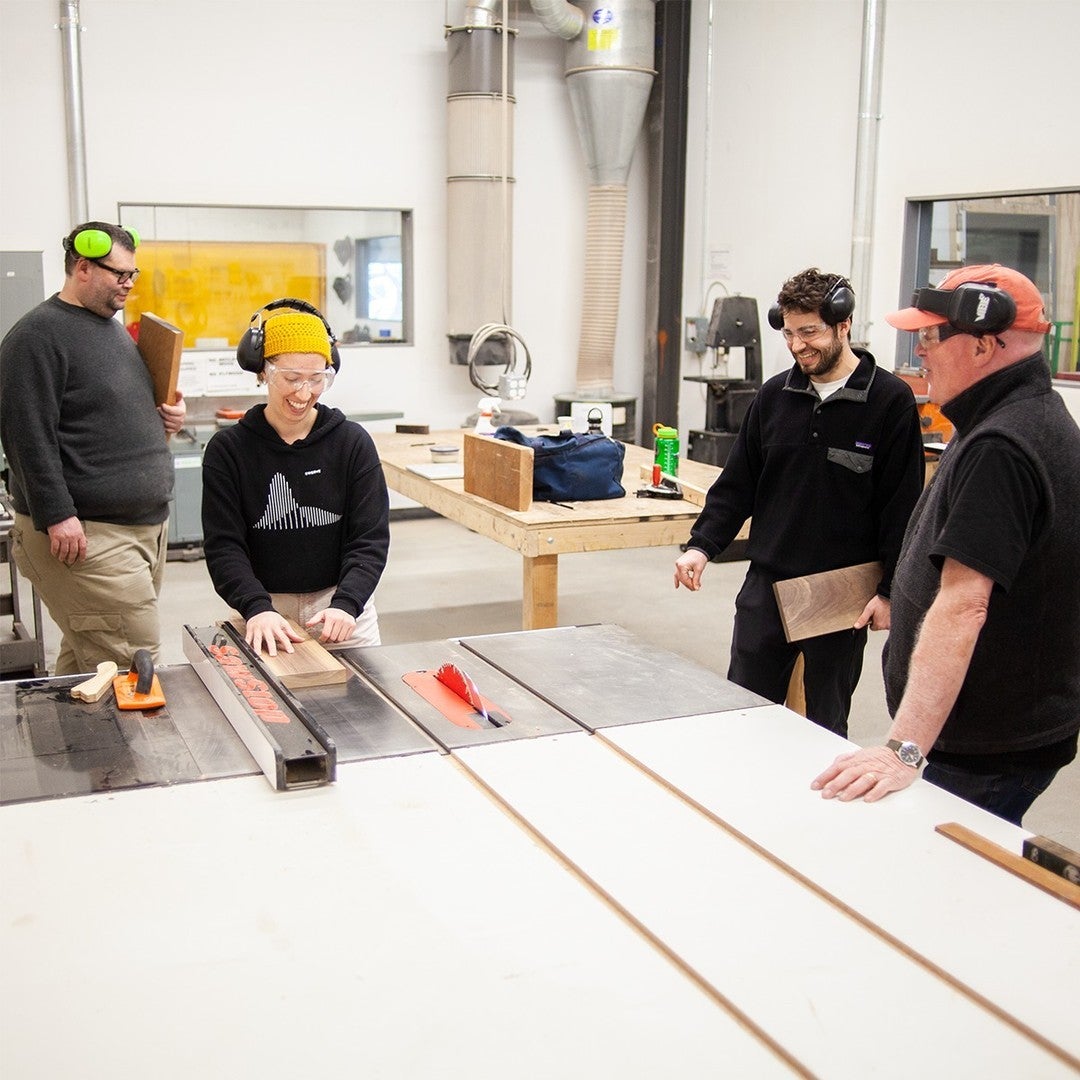 People gather around a tablesaw.