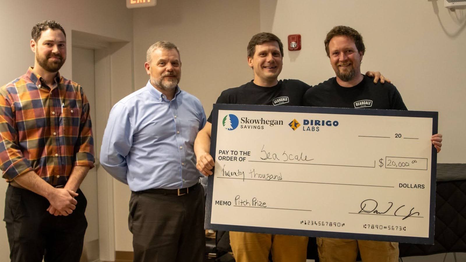 Four people line up with an oversize check.