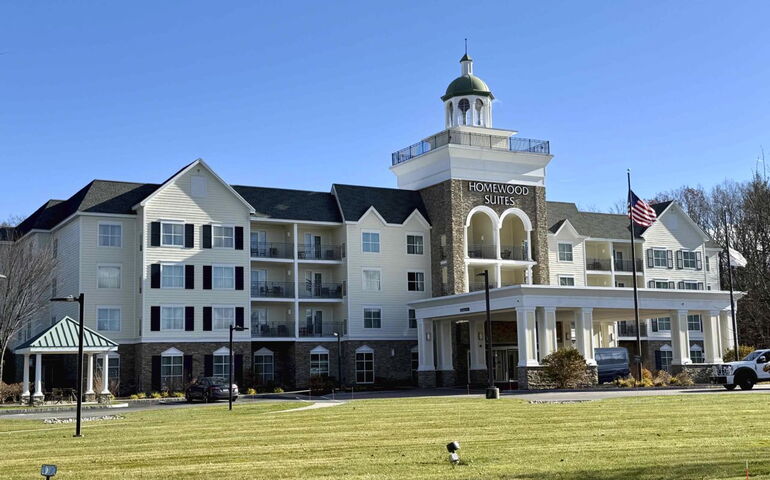 A multi-story building has a flag and lawn.