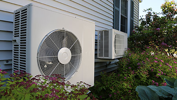 A heat pump is outside of a house.