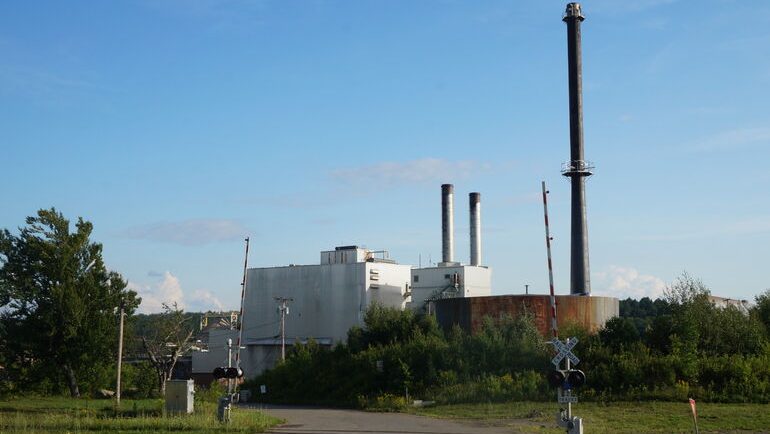 A bunch of industrial buildings sit under a blue sky.